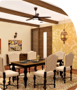 A dining room with wooden slats on the ceiling, a dining table with chairs, wallpaper and painting frames on the walls