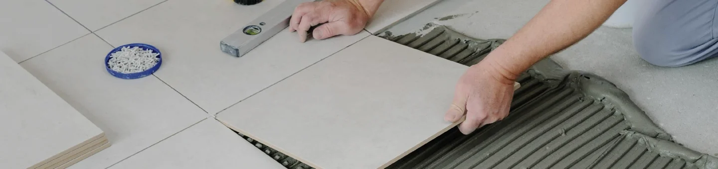 A white tile being placed on the floor