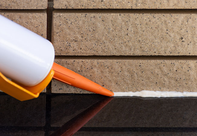 Closeup image of applying silicone sealant by - Asian Paints