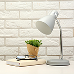 White lamp in white brick background with a small yellow plant pot.