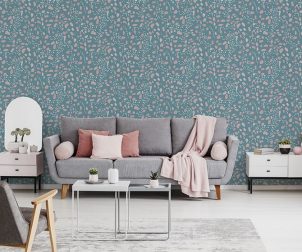 Pink blanket and cushions on grey settee in white flat interior with poster above cupboard. Real photo
