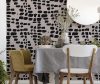 Green velvet and white wooden chairs standing by the dining table with fresh plants, glasses and grey tablecloth in real photo of bright dining room interior with lamp and mirror on the wall