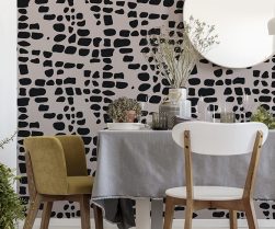 Green velvet and white wooden chairs standing by the dining table with fresh plants, glasses and grey tablecloth in real photo of bright dining room interior with lamp and mirror on the wall Green velvet and white wooden chairs standing by the dining table with fresh plants, glasses and grey tablecloth in real photo of bright dining room interior with lamp and mirror on the wall