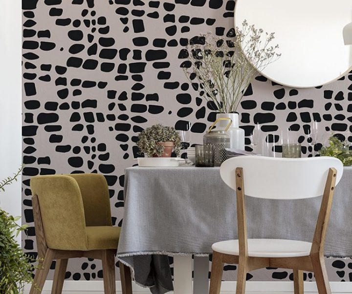 Green velvet and white wooden chairs standing by the dining table with fresh plants, glasses and grey tablecloth in real photo of bright dining room interior with lamp and mirror on the wall
