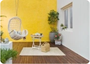 Balcony with a hanging swing chair against a yellow wall in Apex Ultima Allura stone texture